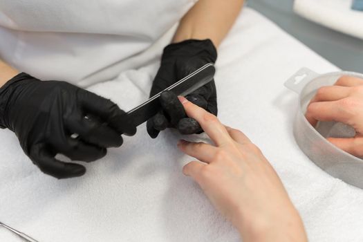 Manicure. Close-up Of Female Hands Filing Nails With Nail File In Beauty Salon. Closeup Of Beautiful Woman Hand With Natural Healthy Nails Polishing Nails With Buffer, Nail Care Tool