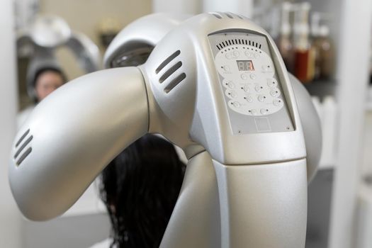Close-up of professional hair dryer dries young girl's hair. Portrait of a girl in a beauty salon. The procedure of moisturizing hair mask in a professional hair salon