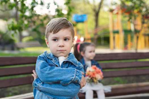 Date of a little boy and a girl in the park with a bouquet of flowers. The boy was offended.