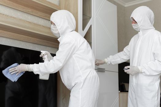 Virologists, people in protective suits carry out the disinfection in the apartment. Wipe furniture and take samples for contamination from the surface during a coronavirus epidemic. Covid - 19.