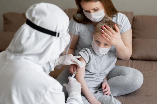 Doctor in personal protective suit or PPE inject vaccine shot to stimulating immunity of a boy at risk of coronavirus infection. Coronavirus,covid-19 and vaccination concept.