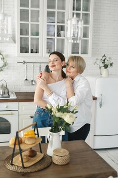 Portrait of two nice attractive lovely tender cheerful women mom adult daughter spending time day together in the kitchen