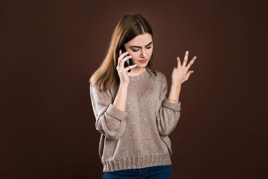 A girl swears on the phone on a brown background