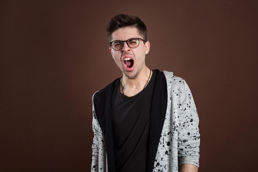 Portrait of a yawning man on a brown background