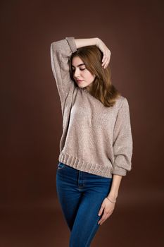 Portrait of a beautiful girl in a sweater on a brown background