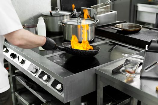 Modern kitchen. Cooks prepare meals on the stove in the kitchen of the restaurant or hotel. The fire in the kitchen