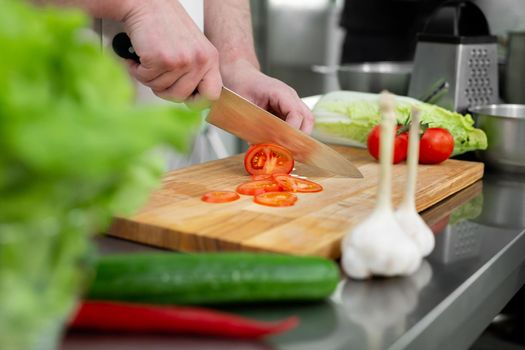 Chef in the kitchen cuts fresh and delicious vegetables for a vegetable salad