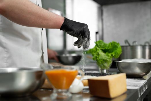 Preparation of the dough for pizza. Close-up of the cook's hand sprinkling the dough with flour.