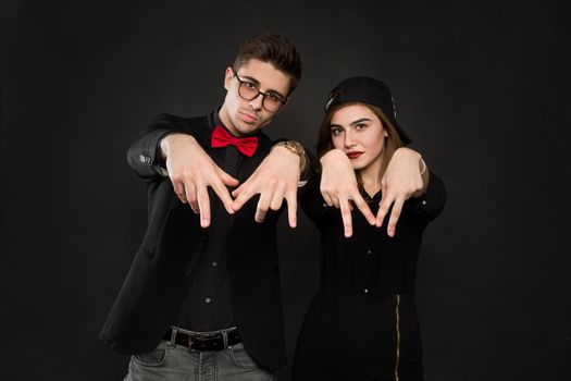 Teenage smiling rap couple in black clothes and a black cap. Isolated over a black background color.