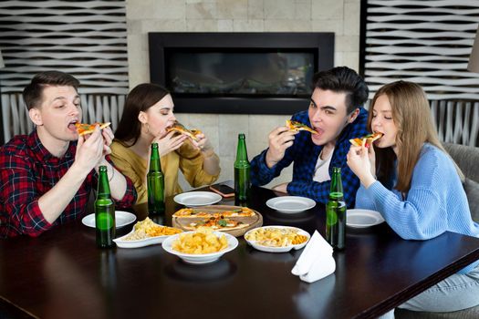 Friends and pizza. Four young cheerful people eating pizza and drinking beer