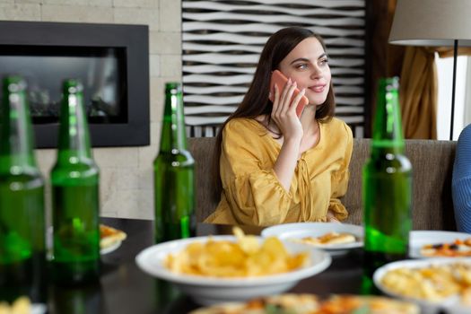 Young woman drinking beer and talking on mobile phone