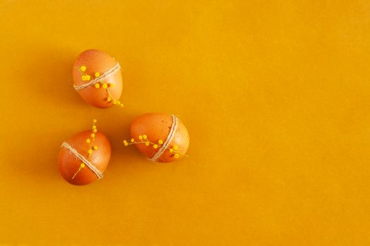 Easter eggs on the yellow background in the sunlight, top view, copy space