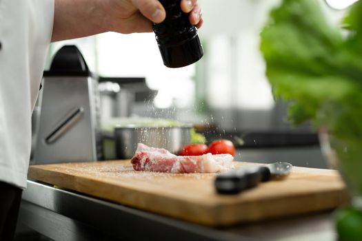 Chef pours salt on beef meat with salt shaker Barbecue