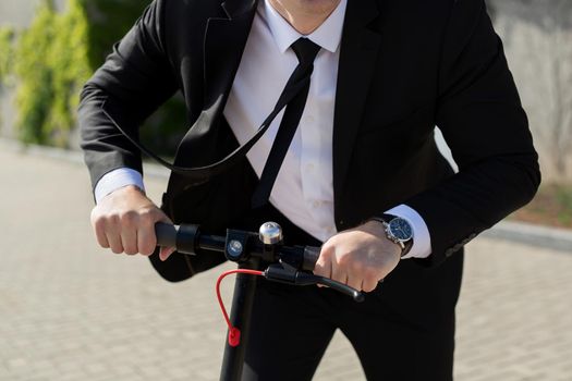Man in a business suit and sunglasses rides an electric scooter and laughs.