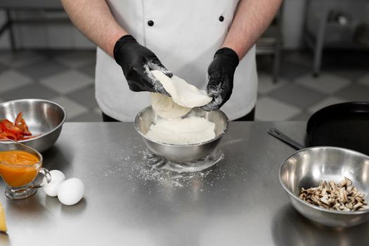 Chef is working in the kitchen with pizza dough