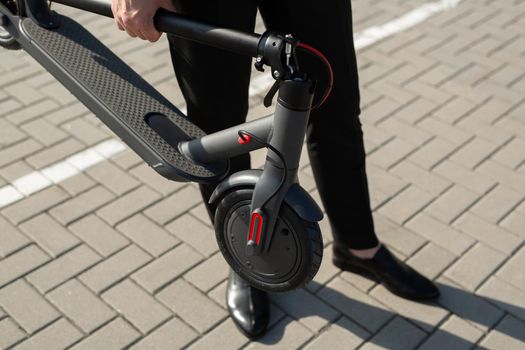 Close-up of a businessman's hands with an electric scooter.