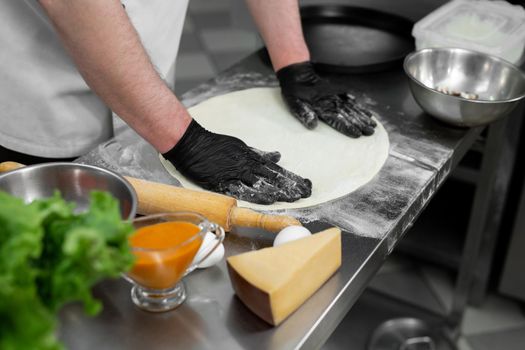 Chef is working in the kitchen with pizza dough