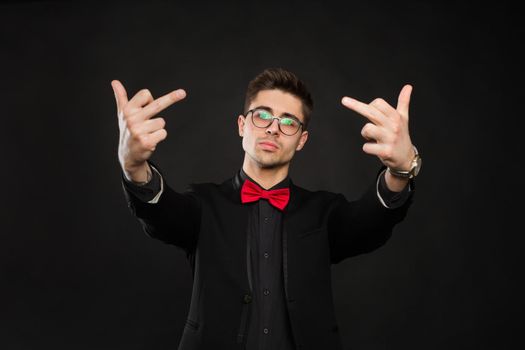 Handsome young man showing middle finger, insult sign on black background