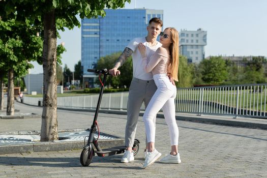 Girl and guy walk on electric scooters around the city, a couple in love on scooters.