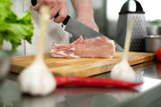 Chef cutting the meat on a wooden board