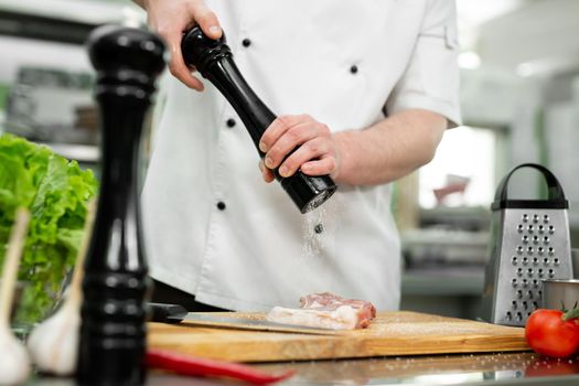 Chef pours salt on beef meat with salt shaker Barbecue
