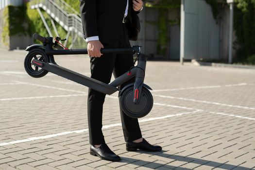 Close-up of a businessman's hands with an electric scooter.