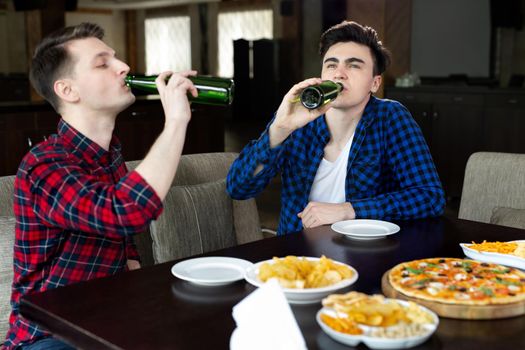 Young men drinking beer and talking in cafe