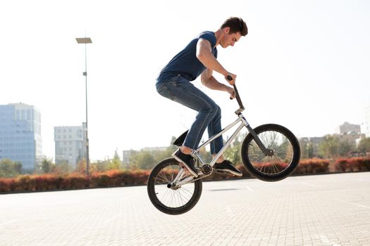 Street portrait of a bmx rider in a jump on the street in the background of the city landscape