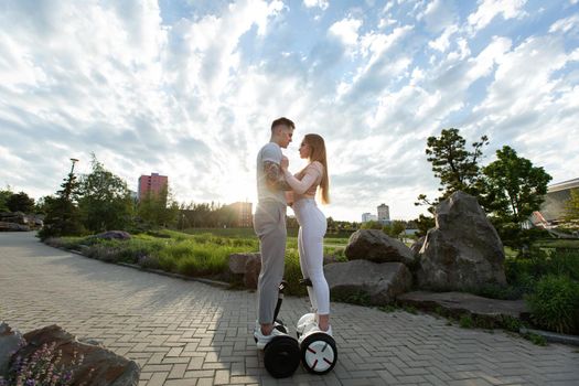 Young man and woman riding on the hoverboard in the park