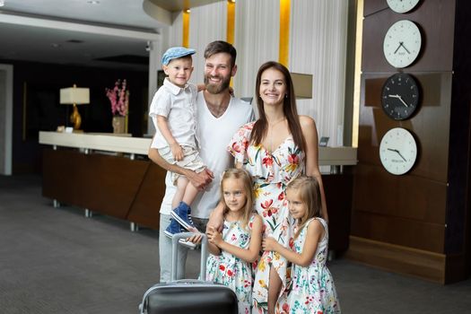 Happy family with luggage near reception desk in hotel.
