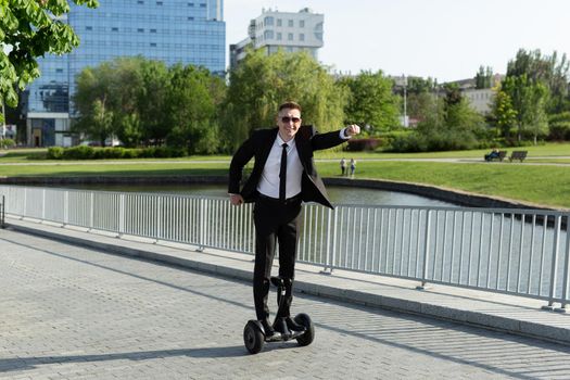 Businessman in a black suit rides a gyro scooter and has fun.
