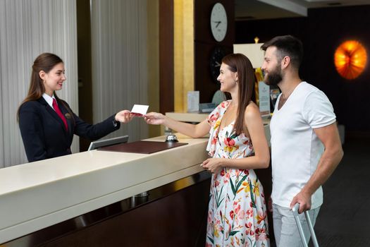 Young couple, husband and wife, check in at the hotel and give their passport.