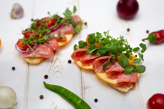 Sandwiches with sausage, cheese and micro-greens on a white background