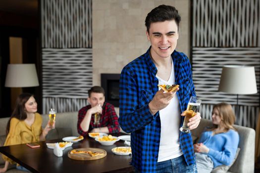 Portrait of a young man holding pizza and beer in a pub