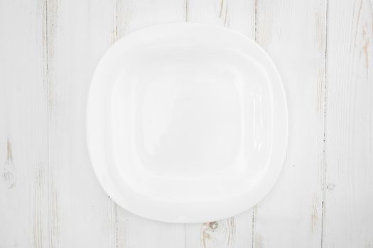 Top view of a white plate on a wooden background.