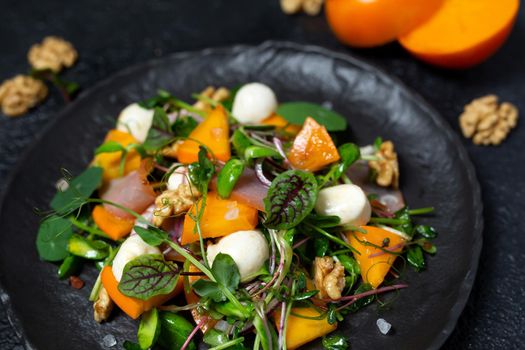 Healthy salad with persimmon, microgreens, nuts and feta cheese. Fitness nutrition.