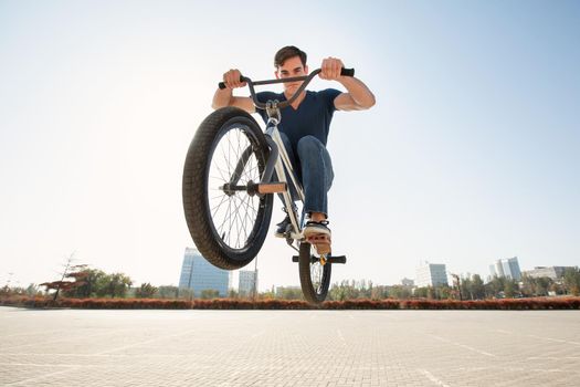 Street portrait of a bmx rider in a jump on the street in the background of the city landscape