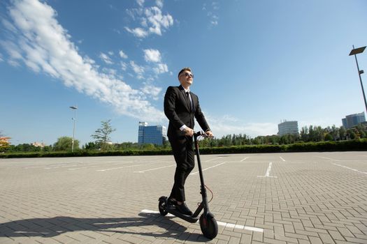 Young businessman in sunglasses on an electric scooter in the city.