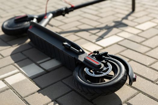 An electric scooter is lying on the sidewalk