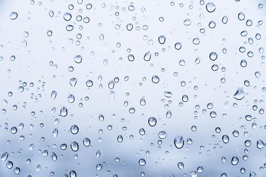 Water drops on glass natural bright blue background. Humidity background.