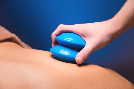 A man's hand places a vacuum rubber cup on the back of a male client.