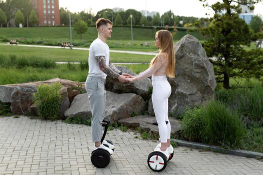 Young man and woman riding on the hoverboard in the park