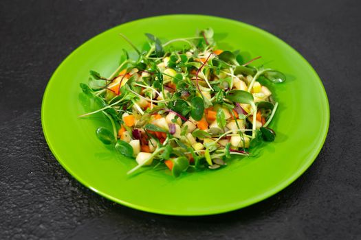 Vitamin salad with vegetables and microgrin on a green plate