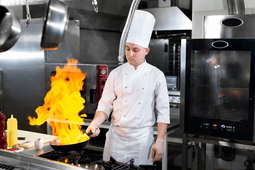 Chef cooking with flame in a frying pan on a kitchen stove