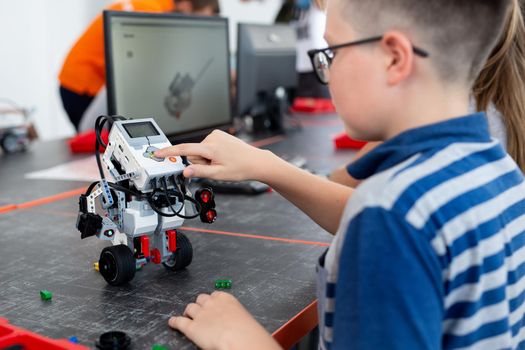 Smart schoolboy sitting at the table and constructing a robotic device in a school lesson