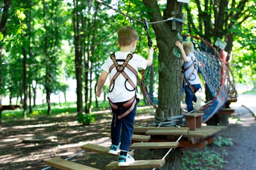 Little active boy who climbs on a rope the way to the amusement Park