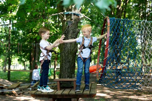 Two little friends say hello while passing the tests in the rope park.