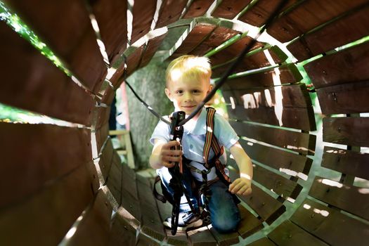 Little active boy who climbs on a rope the way to the amusement Park in the summer