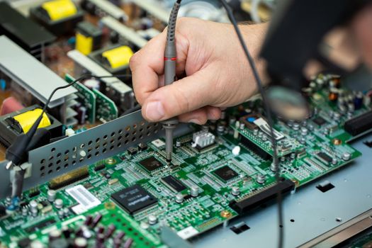 An electrician measures the voltage while repairing an LSD TV in a service center