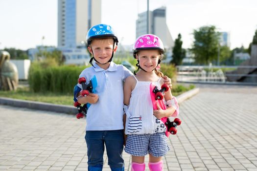 Portrait of small children of a boy and a girl in a park with skates